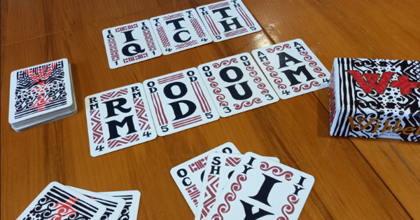 Card game showing cards with 2 letters on them spread on the table along with the ELL deck box