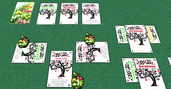 Cards labeled as different varieties of apple tree on the table with apple tokens numbered 1, 2, and 3