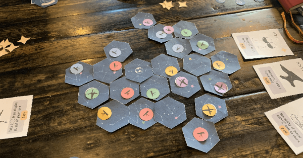 Hexagonal tiles on a table with telescope tokens on them and ability cards on the side