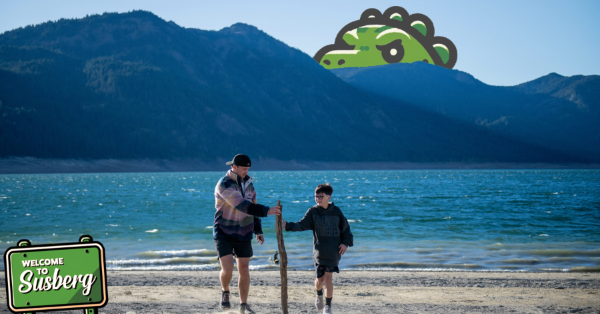 A photograph of an alien dressed in tourist gear at the waterfalls surrounding by other tourists.